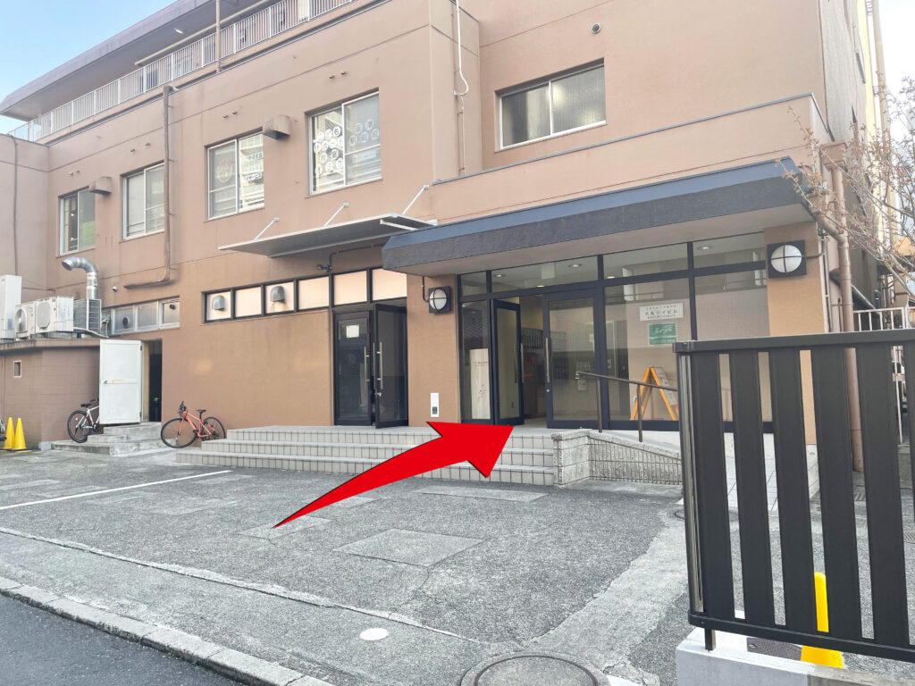 ⑧　右手に茶色のマンションが見えてきます。こちらからお入りください。